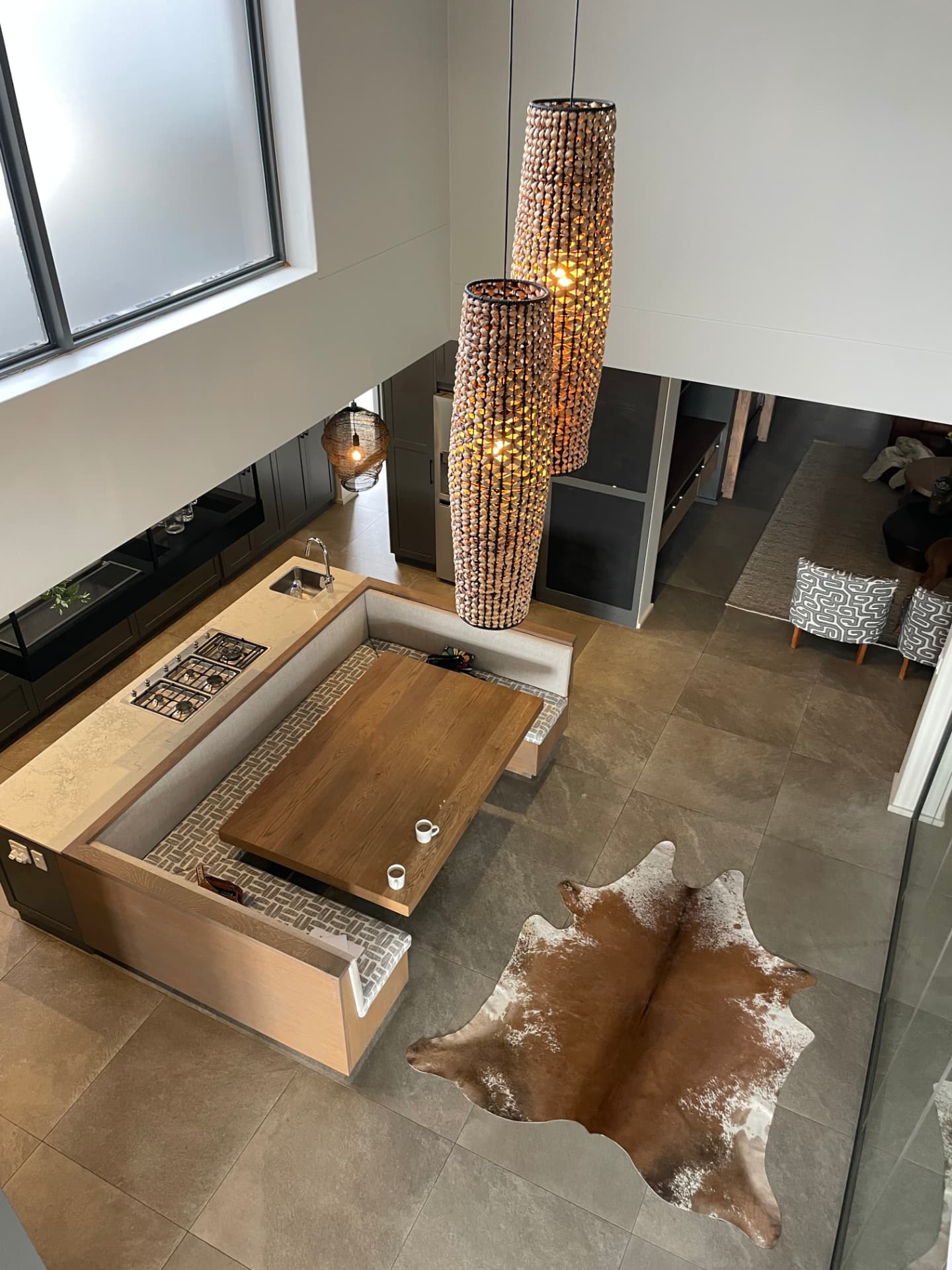 Kitchen and banquette dining seen from above with sculptural beaded pendants