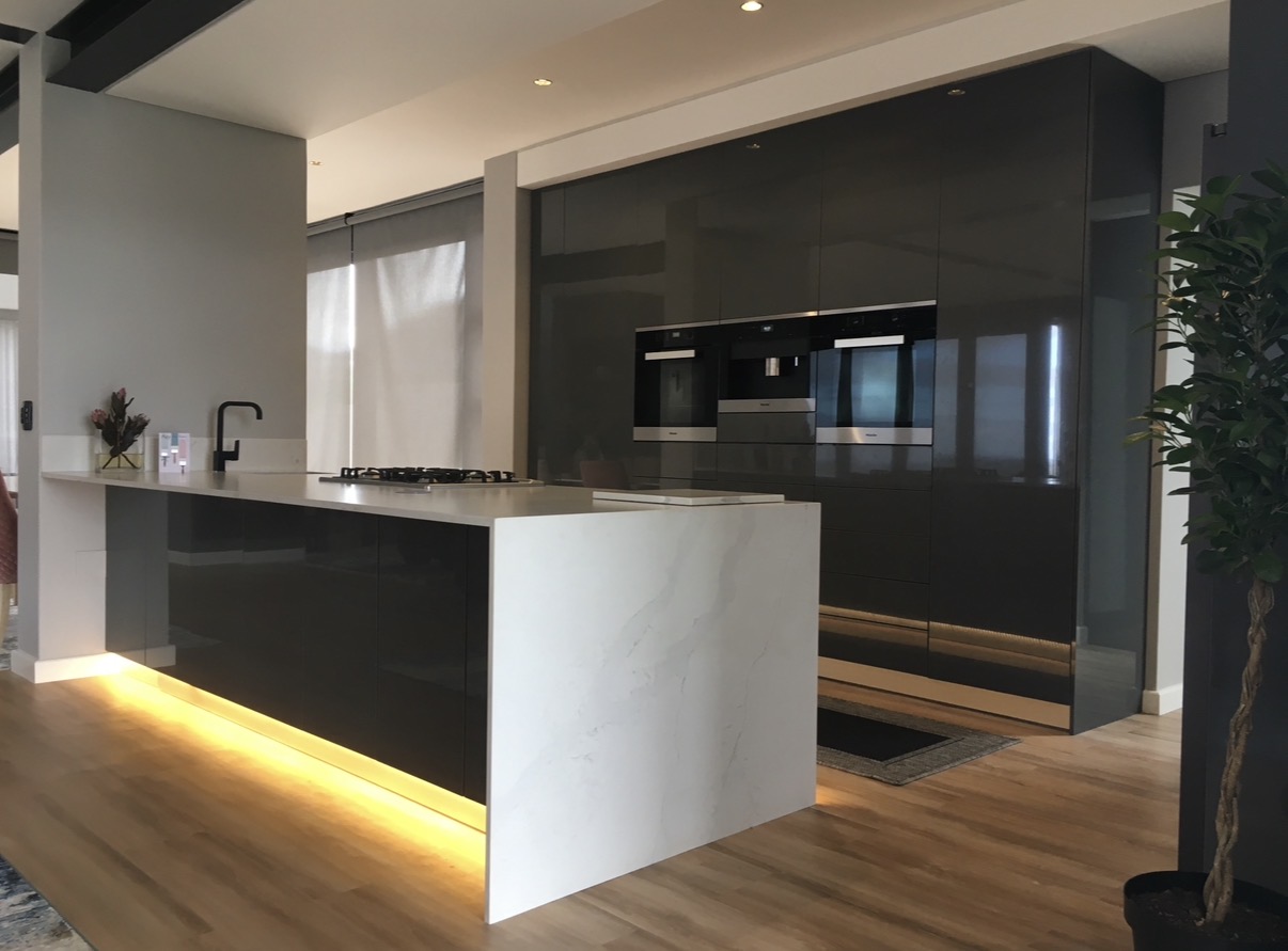 Kitchen with gloss dark cabinetry, marble island and integrated appliances