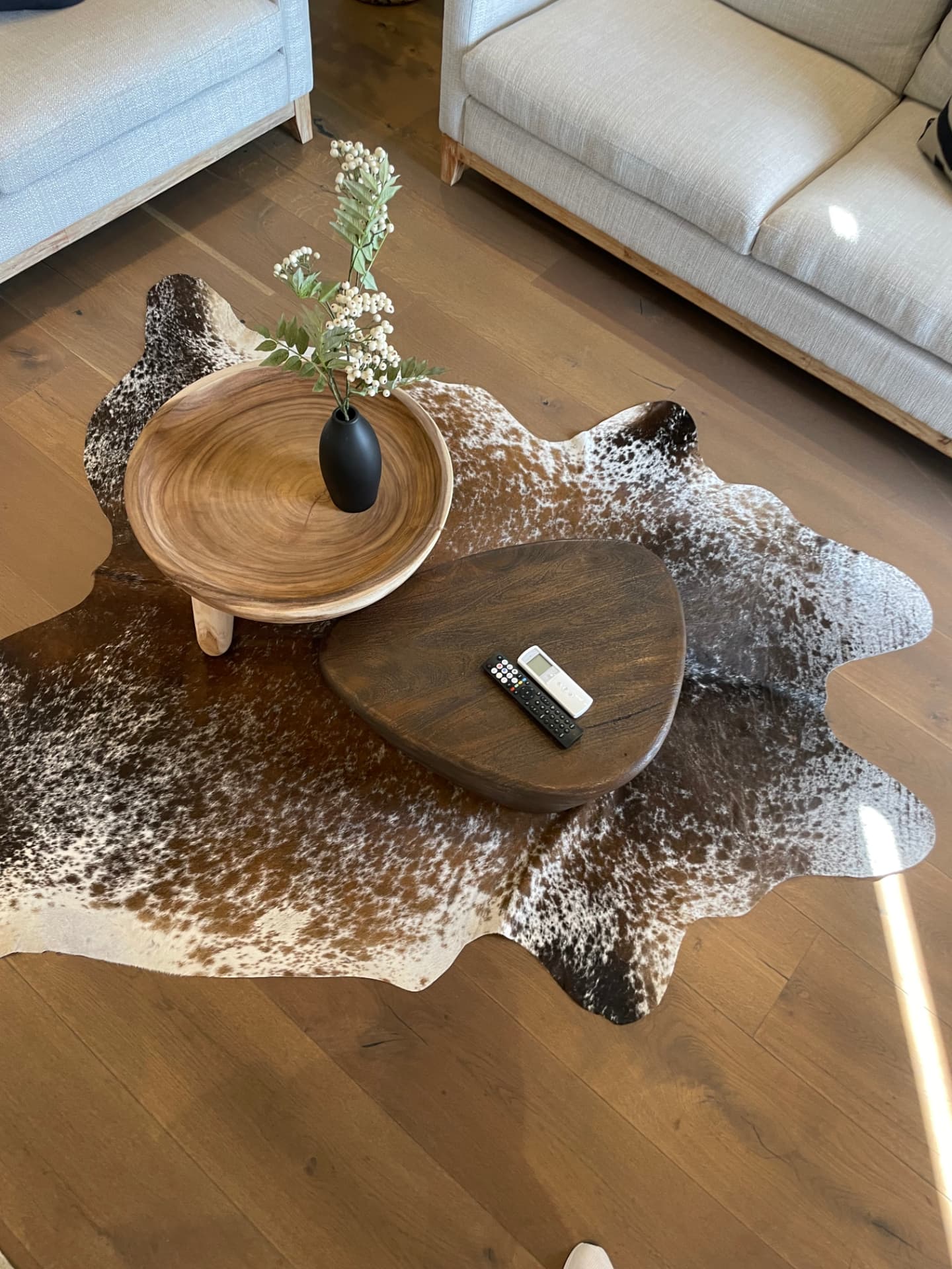 Sculptural timber side tables on a cowhide rug over oak flooring