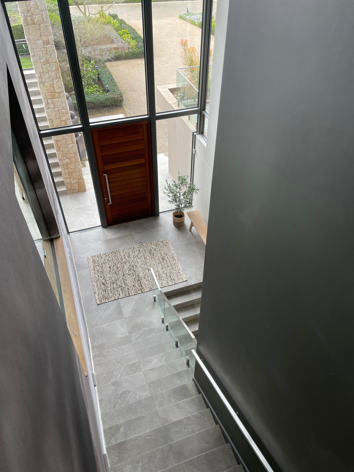 Double-volume entrance hall with timber pivot door and stone stair