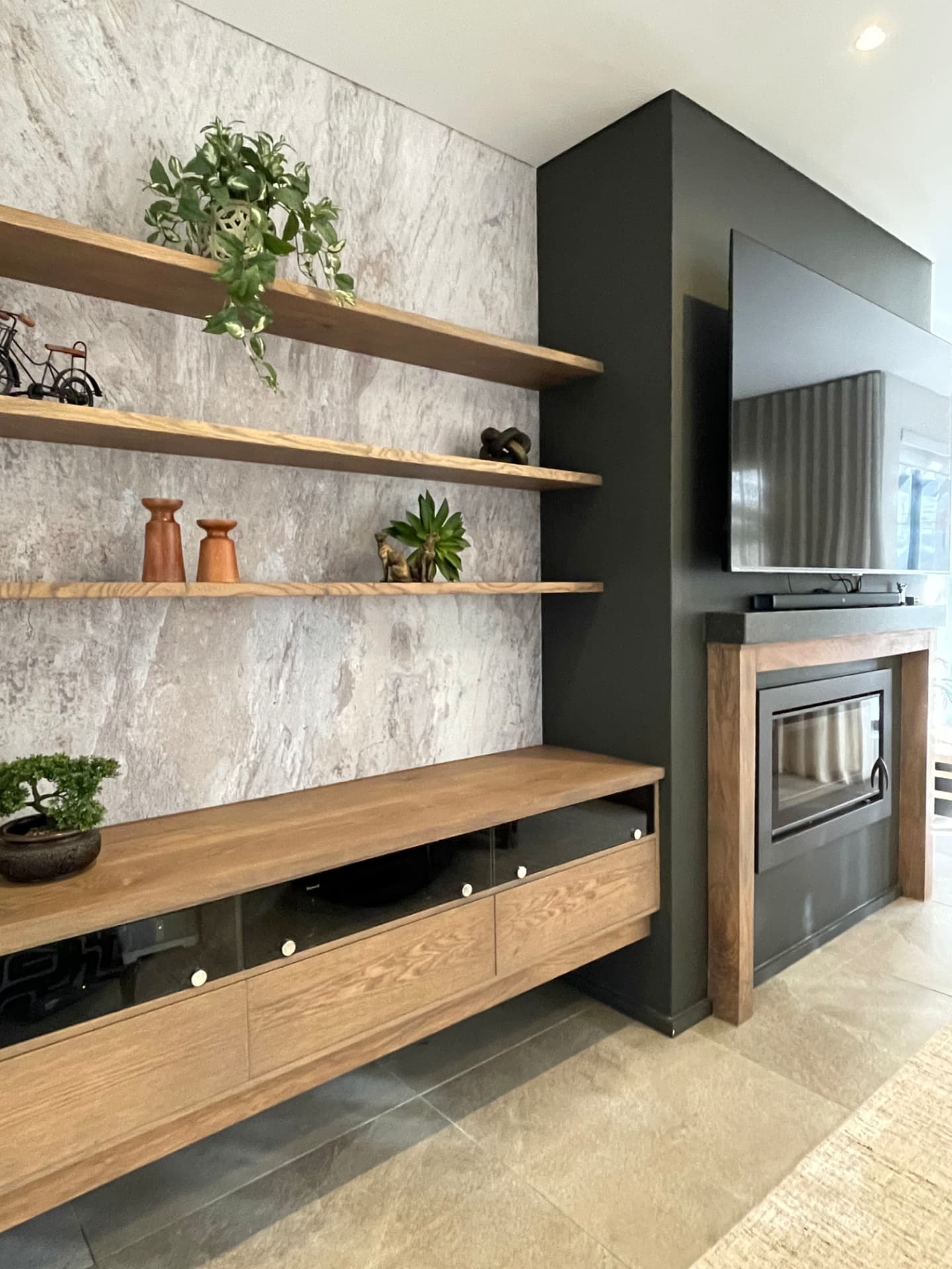 Floating oak shelving against stone-clad wall beside a built-in fireplace
