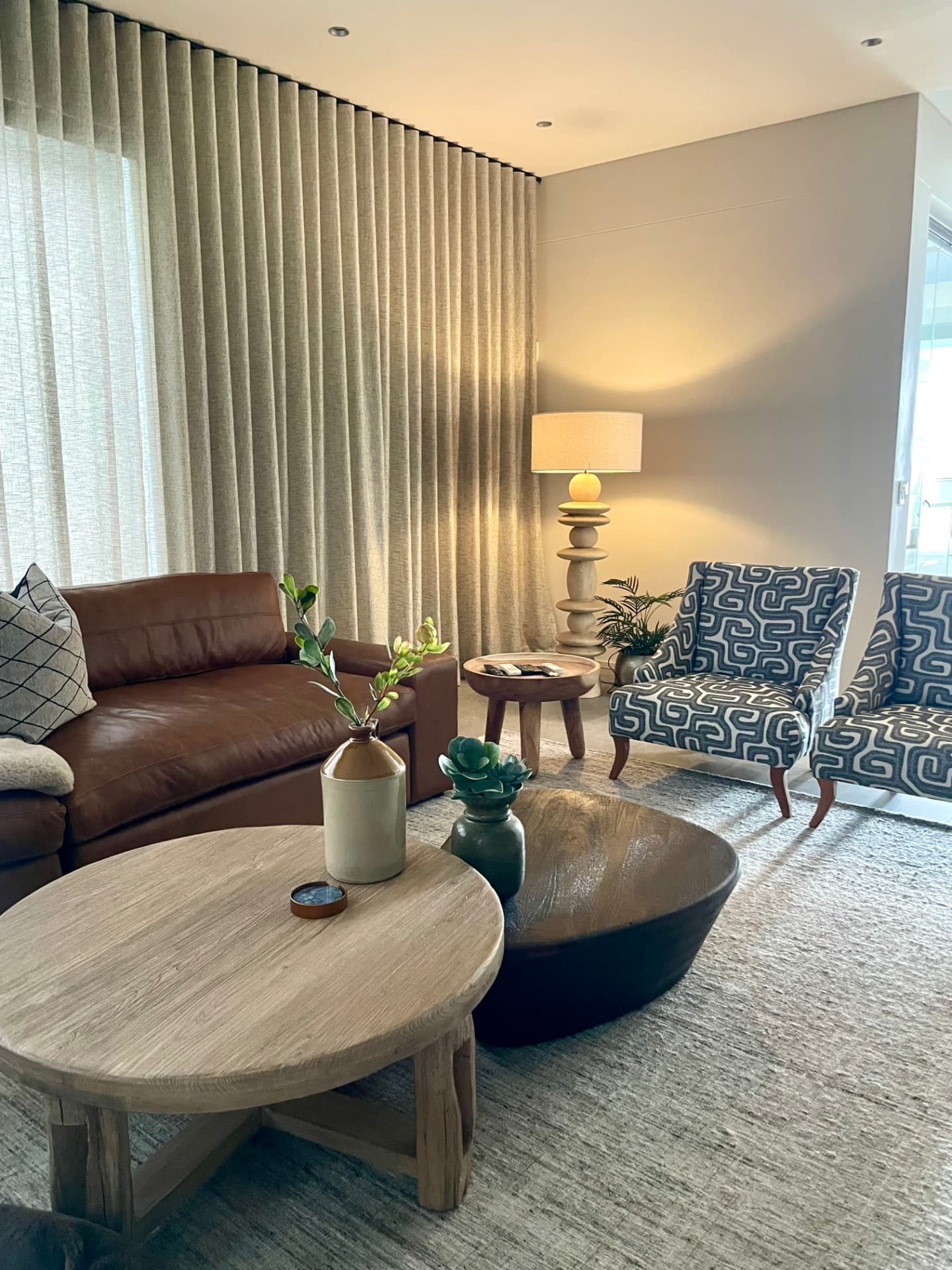 Lounge with sheer linen curtaining, leather sofa and patterned wing chairs
